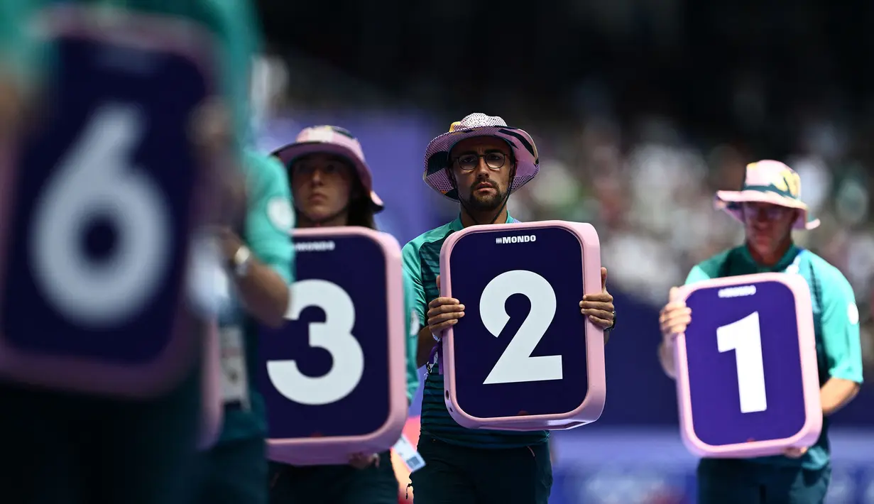 Para volunteer sedang bersiap memasang nomor lintasan untuk nomor lari 800m putra cabang atletik Olimpiade Paris 2024 di Stade de France, Paris, Prancis pada 7 Agustus 2024. (AFP/Jewel Samad)