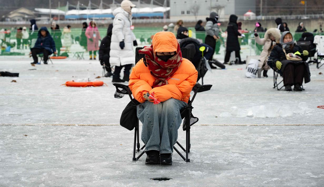 Festival Tahunan Memancing di Atas Es Hwacheon tahun 2026 secara resmi dibuka hari ini, Sabtu 10 Januari 2026, dan akan berlangsung hingga 1 Februari 2026. Tampak dalam foto, seorang wanita memancing melalui lubang di sungai yang membeku selama festival tahunan memancing di atas es, Hwacheon, Korea Selatan, pada Sabtu 10 Januari 2026. (Shin Yong-ju/AFP)