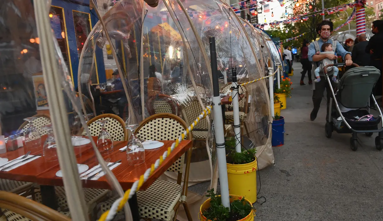 Orang-orang menikmati makanan di dalam tenda plastik untuk menjaga jarak di sebuah restoran di Manhattan, New York City, Kamis (15/10/2020). Konsep gelembung luar angkasa ini menawarkan sensasi tersendiri sekaligus berjaga-jaga dari resiko penularan COVID-19 bagi para pelanggan. (Angela Weiss/AFP)