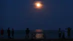Warga mengamati keindahan supermoon yang terlihat di atas Pantai Sanur, Bali, Senin (14/11). Fenomena ini terjadi saat bulan mencapai titik terdekat dengan bumi dan merupakan fenomena supermoon terbesar dalam 68 tahun terakhir. (SONNY TUMBELAKA/AFP)