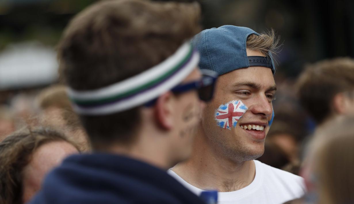 Seorang fans dengan gambar bendera Inggris sedang antri memasuki lapangan guna menonton Tenis Wimbledon Championships 2016 di The All England Lawn Tennis Club, Wimbledon,  London, (27/6/2016). (AFP/Adrian Dennis)