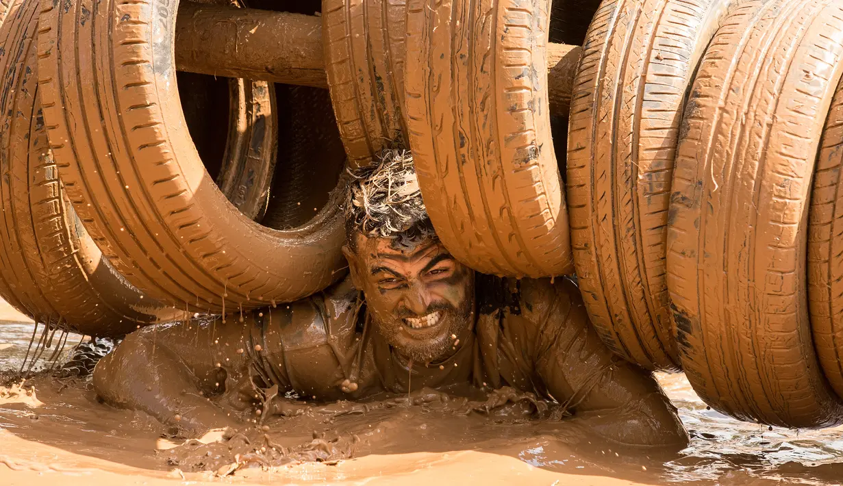 Ekspresi peserta dengan tubuh penuh lumpur saat mengikuti Mud Day di Tel Aviv, Israel (16/3). Dalam acara ini para peserta harus melewati rintangan sepanjang 13 kilometer. (AFP Photo/Jack Guez)