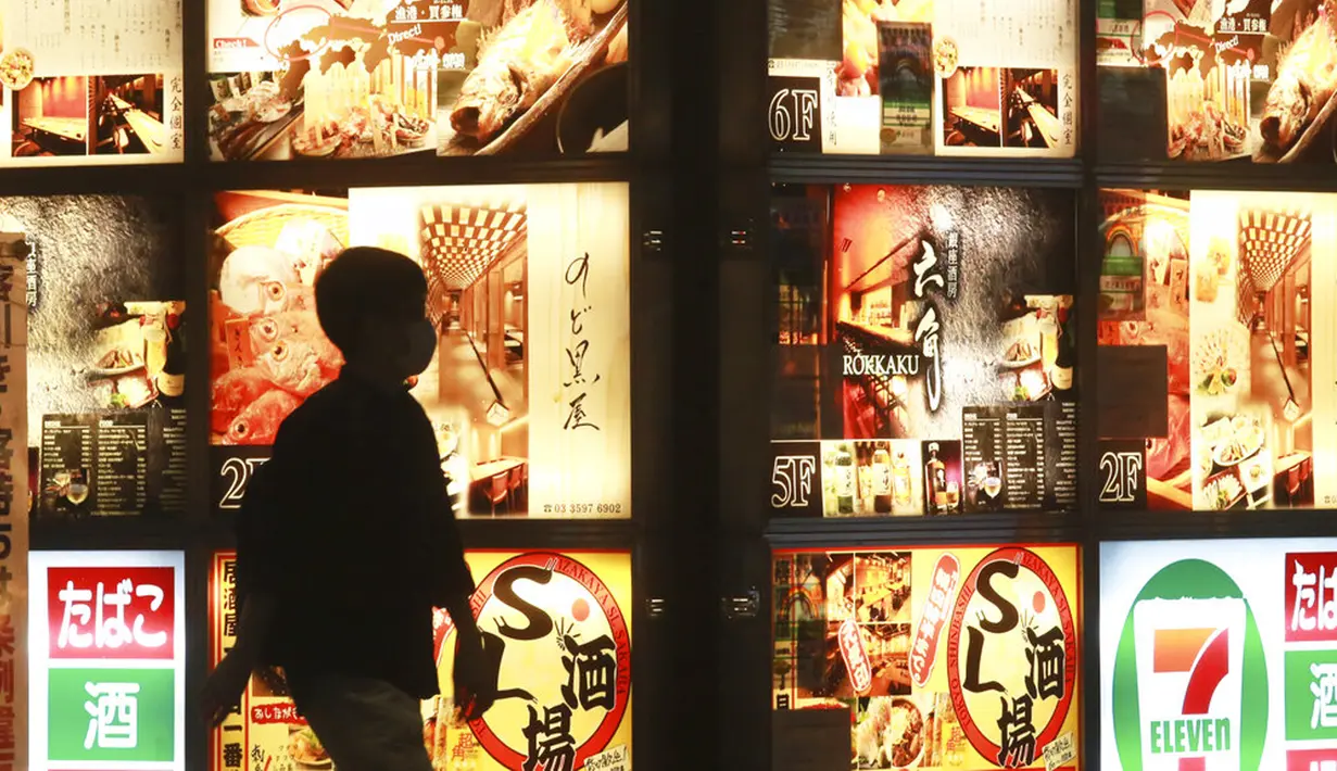 Seorang pria berjalan melewati cahaya iklan restoran di sepanjang jalan di Tokyo, Jepang, 4 Oktober 2021. Warga kembali beraktivitas setelah berakhirnya status pembatasan darurat virus corona COVID-19 di Jepang. (AP Photo/Koji Sasahara)