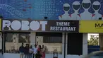 Pengunjung berpose di luar restoran bertema robot di Chennai, India (20/12). Restoran ini merupakan yang pertama di India yang memiliki pelayan robot dengan server otomatis membawa piring dari dapur ke pelanggan. (AFP Photo/Arun Sankar)