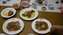 Pramusaji menyajikan hidang dari daging anjing  di restoran khusus anjing, Pyongyang House of Sweet Meat, Rabu (25/7). Masyarakat Korea percaya bahwa panas akan menyembuhkan panas sehingga mereka makan daging anjing saat cuaca panas. (AP/Dita Alangkara)