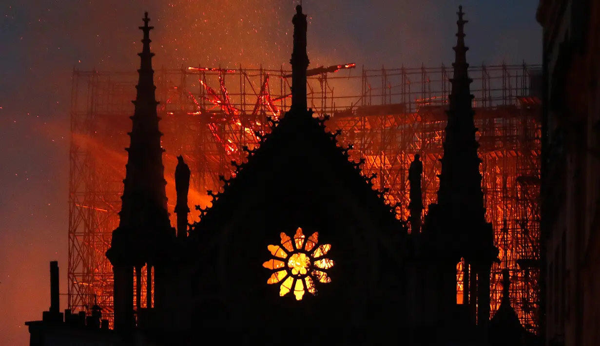 Api dan asap mengepul dari kebakaran Gereja Katedral Notre-Dame di pusat kota Paris, Prancis, pada Senin (15/4) waktu setempat. Api dengan cepat melalap bagian atap gereja yang dibangun pada abad ke-12 itu dan merupakan salah satu ikon wisata di Paris. (AP Photo/Thibault Camus)