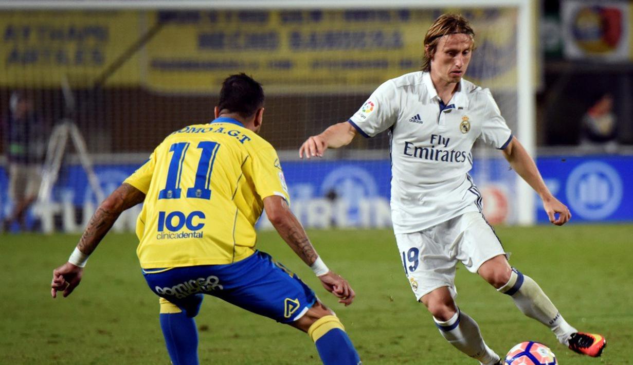 Pemain Real Madrid, Luka Modric, berusaha melewati pemain Las Palmas, Momo, dalam lanjutan La Liga di Gran Canaria, Las Palmas, Minggu (25/9/2016) dini hari WIB. (AFP/Desiree Martin)