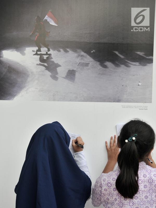 Siswa SD Negeri Menteng 01 menulis keterangan pada salah satu karya foto dalam pameran fotografi Rekam Jakarta di Taman Menteng, Kamis (29/8/2019). Kegiatan tersebut dalam rangka edukasi bagi siswa mengenal profesi foto jurnalistik. (merdeka.com/Iqbal S Nugroho)