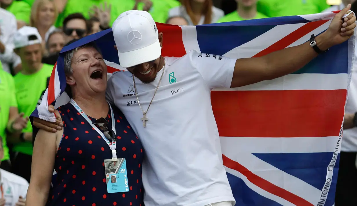 Pembalap asal Inggris dari tim Marcedes, Lewis Hamilton bersama ibunya, Carmen Larbalestier merayakan kemenangannya meraih juara dunia F1 untuk yang ke empat kalinya di Autodromo Hermanos Rodrigue, Meksiko (29/10). (AP Photo / Rebecca Blackwell)
