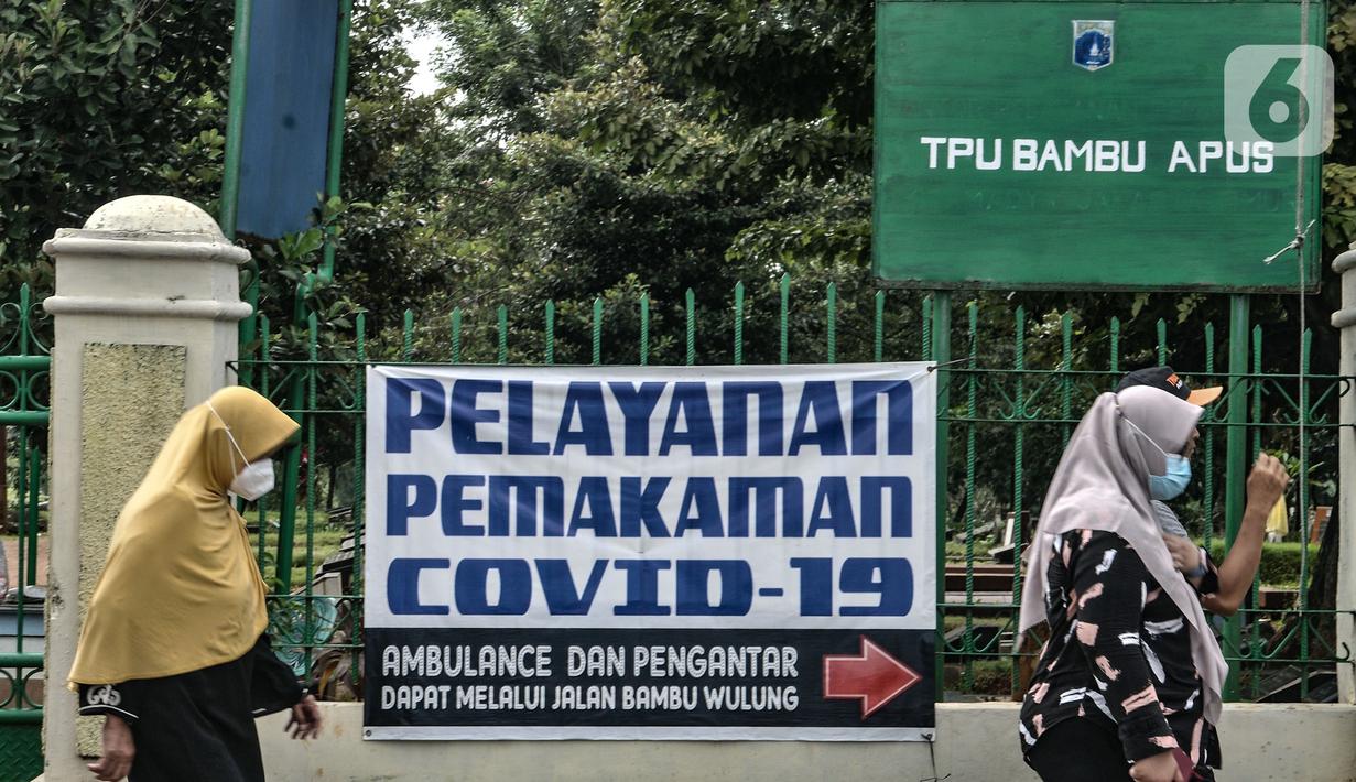 Warga melintas di depan kompleks makam protokol Covid-19 di TPU Bambu Apus, Jakarta, Selasa (2/3/2021). TPU Bambu Apus kini tidak lagi menampung pemakaman jenazah protokol Covid-19 akibat lahan di dua blok sudah penuh dan dialihkan ke TPU Srengseng Sawah. (merdeka.com/Iqbal S Nugroho)