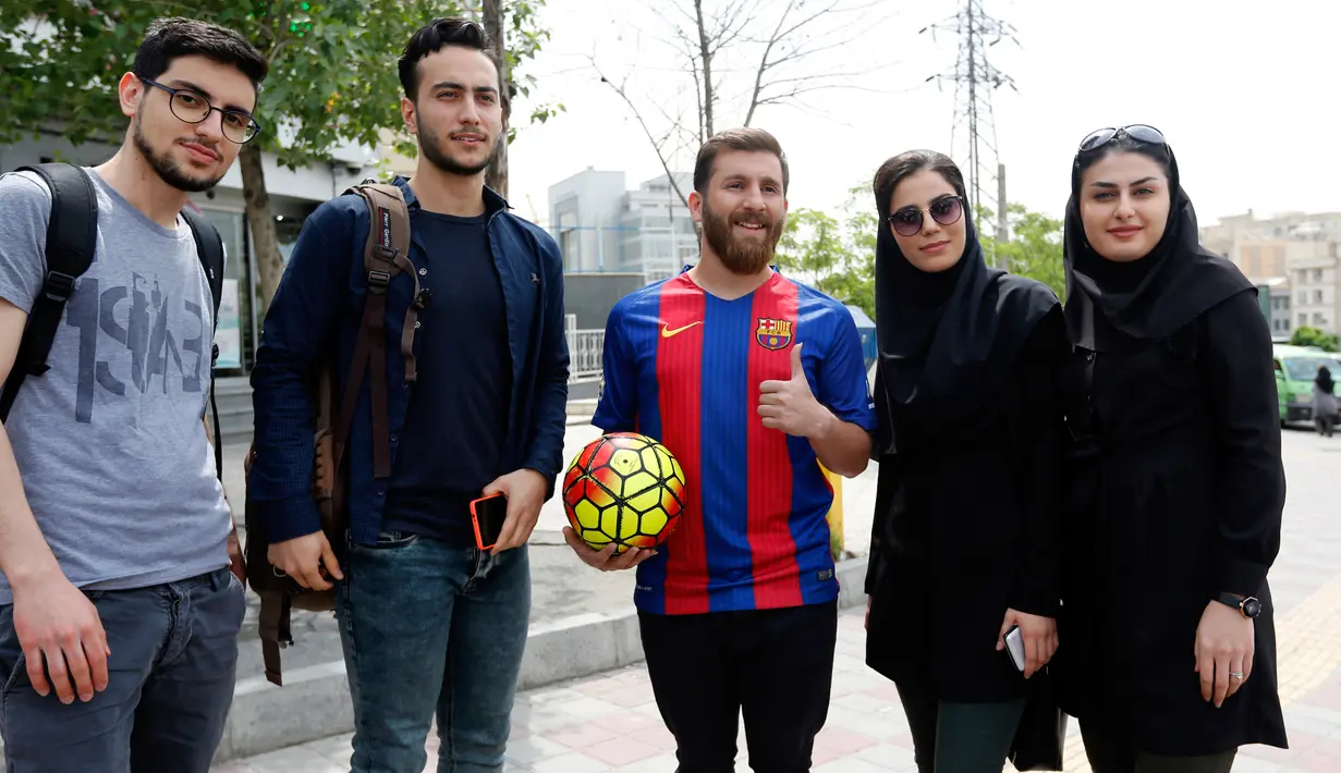 Pemuda asal Iran, Reza Parastesh berswafoto dengan penggemarnya di sebuah jalan di Teheran, Senin (8/5). Kemiripan pria 25 tahun itu dengan bintang Barcelona Lionel Messi membuat banyak orang ingin berfoto bersama bahkan hingga berebutan (ATTA KENARE/AFP)