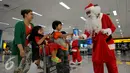 Santa Claus memberikan hadiah kepada anak-anak di Bandara Soekarno Hatta, Tangerang, Banten, Selasa (22/12). Sejumlah orang berkostum santa claus membagikan coklat kepada penumpang yang berada dibandara. (Liputan6.com/Faisal R Syam)