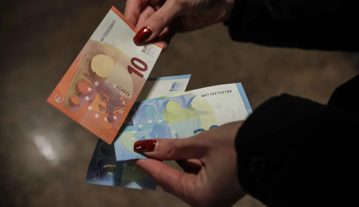 Namun mulai 1 Februari 2026, euro akan menjadi satu-satunya alat pembayaran yang sah di seluruh wilayah Bulgaria. Tampak dalam foto, seseorang menunjukkan uang kertas euro yang ditarik dari ATM di Sofia, Bulgaria, Kamis 1 Januari 2026, saat negara tersebut bergabung dengan serikat mata uang euro. (AP Photo/Valentina Petrova)