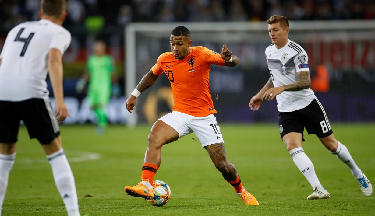 Penyerang Belanda,  Memphis Depay (tengah) mengontrol bola dari kejaran gelandang Jerman, Toni Kroos (kanan) saat bertanding pada grup C  kualifikasi Euro 2020 di Hamburg, Jerman (6/9/2019). Belanda menang telak 4-2 atas Jerman. (AFP Photo/Odd Andersen)