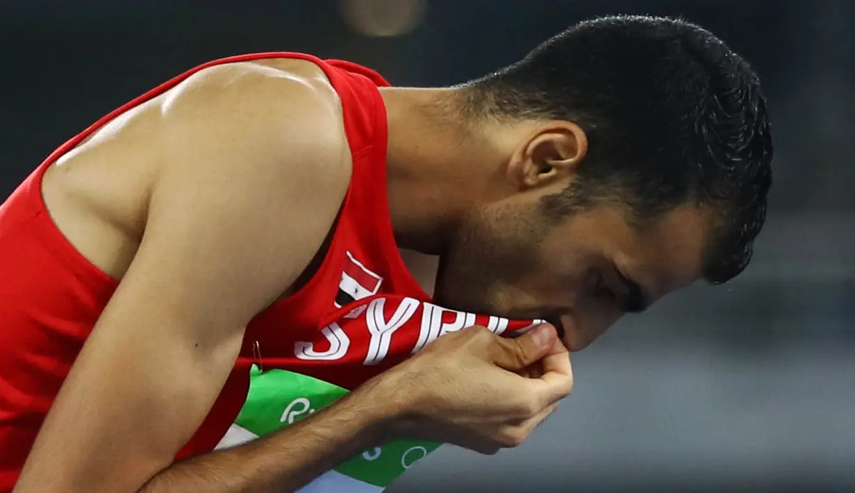 Atlet lompat tinggi Suriah, Majd Eddin Ghazal, mencium bendera negaranya usai tampil pada Olimpiade 2016 di Rio de Janeiro, Brasil, Sabtu (20/8/2016). Konflik dalam negeri tak menyurutkan semangat para atlet dari Suriah. (Reuters/Kai Pfaffenbach)