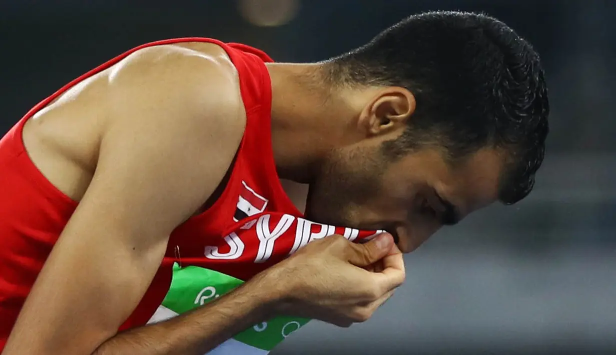 Atlet lompat tinggi Suriah, Majd Eddin Ghazal, mencium bendera negaranya usai tampil pada Olimpiade 2016 di Rio de Janeiro, Brasil, Sabtu (20/8/2016). Konflik dalam negeri tak menyurutkan semangat para atlet dari Suriah. (Reuters/Kai Pfaffenbach)