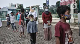 Anak-anak didampingi orang tua berbaris dengan standar protokol kesehatan saat antre menerima donasi ponsel yang diberikan Komunitas #WartawanLintasMedia saat acara #PonselPintarUntukPelajar di Jakarta, Minggu (9/8/2020). (merdeka.com/Iqbal S. Nugroho)