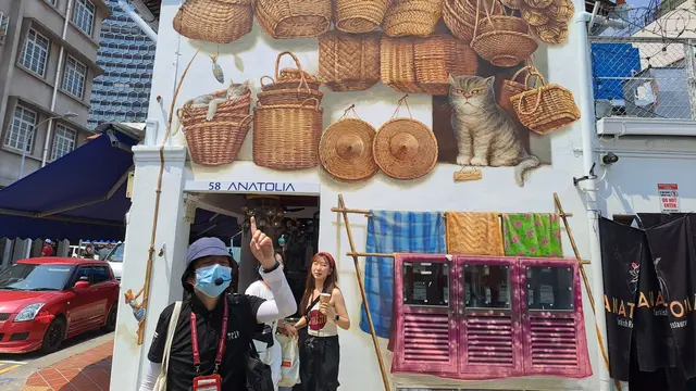 Pemandu tur Andros Wong menceritakan kisah mural di Bussorah Street, Singapura (Foto: Liputan6.com/Agustina Melani)