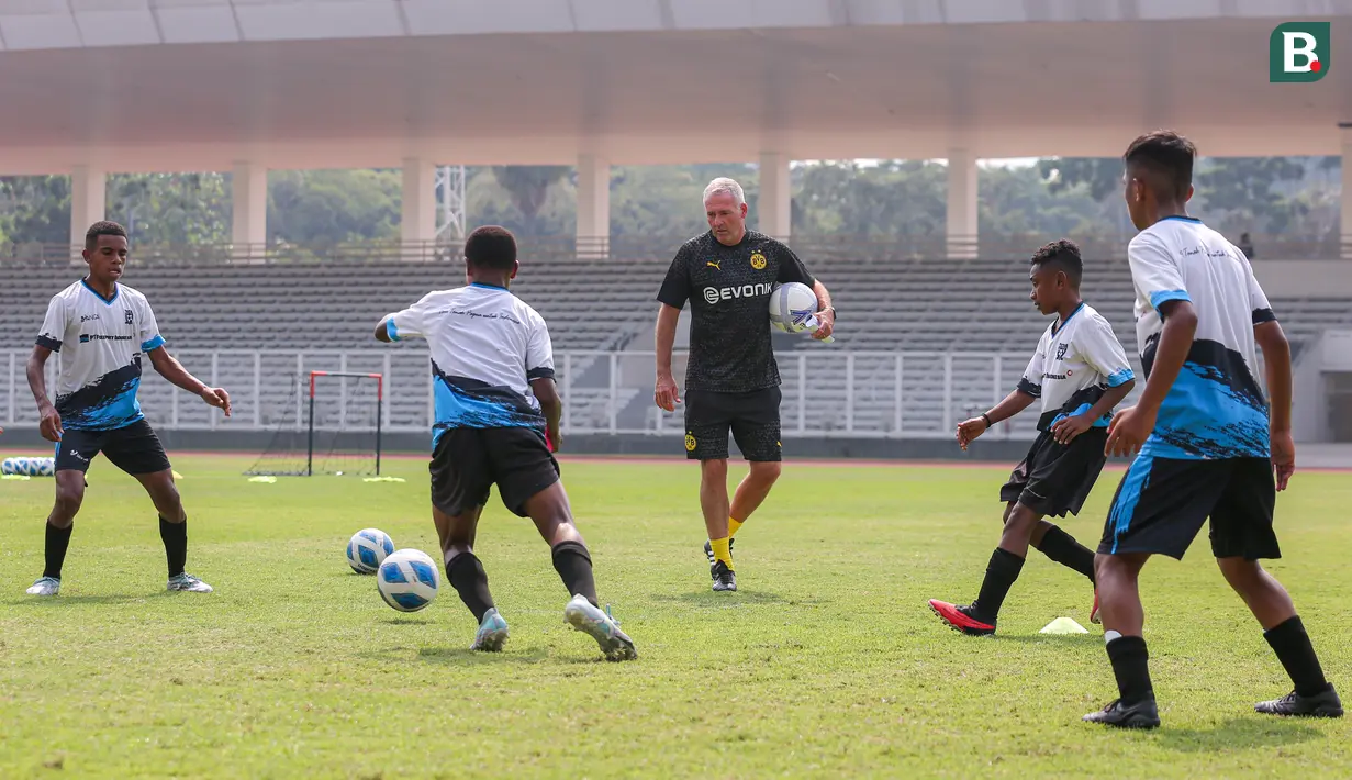 Legenda Borussia Dortmund Paul Lambert (tengah) memberikan coaching clinic kepada kepada siswa Papua Football Academy di Stadion Madya, Senayan, Jakarta, Jumat (08/09/2023). (Bola.com/Bagaskara Lazuardi)