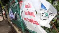 Spanduk salah satu parpol dan caleg peserta Pemilu 2019 terlihat sobek terpampang di pagar pembatas di Jalan Raya Bogor, Jakarta, Kamis (17/1). Kondisi ini membuat pagar pembatas terlihat kumuh. (Liputan6.com/Helmi Fithriansyah)