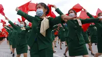 Wanita yang mengenakan masker wajah untuk membantu mengekang penyebaran virus corona COVID-19 berparade dengan bendera saat rapat umum menyambut Kongres ke-8 Partai Buruh Korea di Lapangan Kim Il Sung, Pyongyang, Korea Utara, Senin (12/10/2020). (AP Photo/Jon Chol Jin)