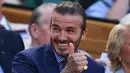 Senyum David Beckham saat menyaksikan dari Royal Box pada hari kelima di Kejuaraan Tenis Wimbledon 2017 di London, Inggris (7/7). Beckham tampil dengan jas berwarna biru dan menggunakan kaca mata hitam. (AFP Photo/Glyn Kirk)