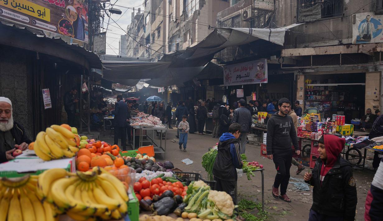 Meski masih terbatas, pasokan kebutuhan harian mulai mengalir deras ke pasar-pasar di Jalur Gaza. Tampak dalam foto, warga Palestina berjalan di sepanjang pasar jalanan tempat buah-buahan dan sayuran dipajang untuk dijual di Kota Gaza, Jumat, 19 Desember 2025. (AP Photo/Abdel Kareem Hana)
