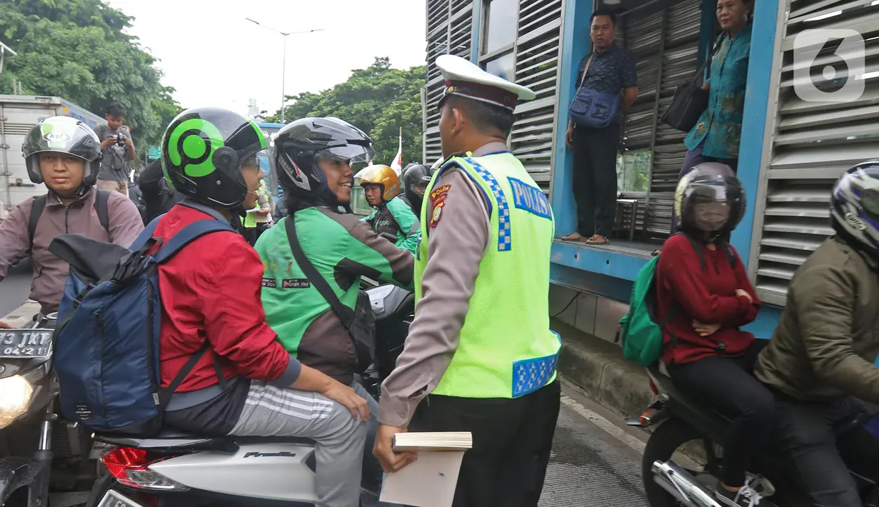 Polisi memberhentikan pengendara sepeda motor yang menerobos jalur Transjakarta di Jalan Sultan Agung, Manggarai, Jakarta, Rabu (12/2/2020). Pengendara kerap melintasi jalur Transjakarta untuk menghindari kemacetan lalu lintas. (Liputan6.com/Herman Zakharia)