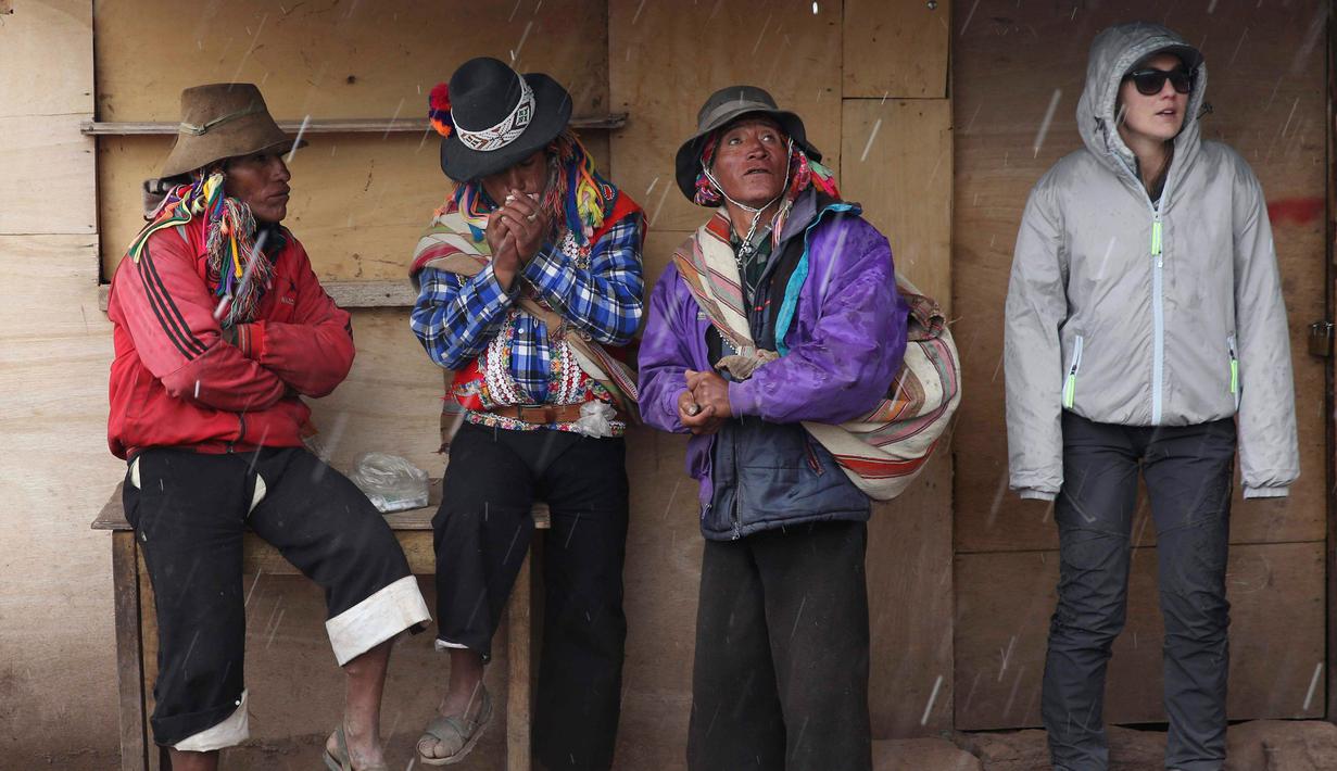 Sejumlah pria Andean dan seorang wisatawan meneduh saat hujan di Gunung Pelangi di Pitumarca, Peru (5/4). Rainbow Mountain terdiri dari hamparan pasir berwarna-warni seperti pelangi. (AP Photo/Martin Mejia)