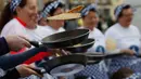 Peserta melemparkan pancake mereka sebelum mengambil bagian dalam lomba lari sembari membawa wajan di Olney, Buckinghamshire, Inggris, Selasa (25/2/2020). Para peserta kompetisi tahunan tersebut harus membolak-balikan pancake sambil tetap berlari. (AP/Alastair Grant)