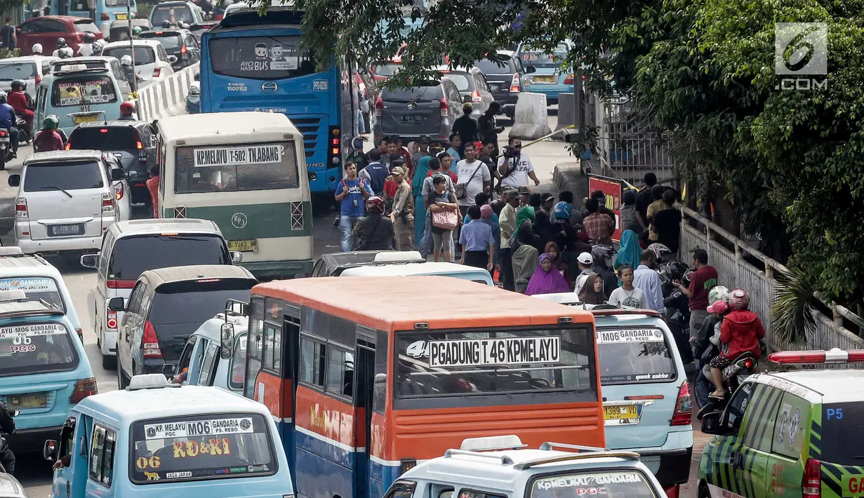 Sejumlah orang berada di pinggir trotoar saat kendaraan terjebak kemacetan di kawasan Terminal Kampung Melayu menuju Jatinegara, Kamis (25/5). Kemacetan itu imbas banyaknya warga yang mendatangi lokasi bom Kampung Melayu. (Liputan6.com/Faizal Fanani)