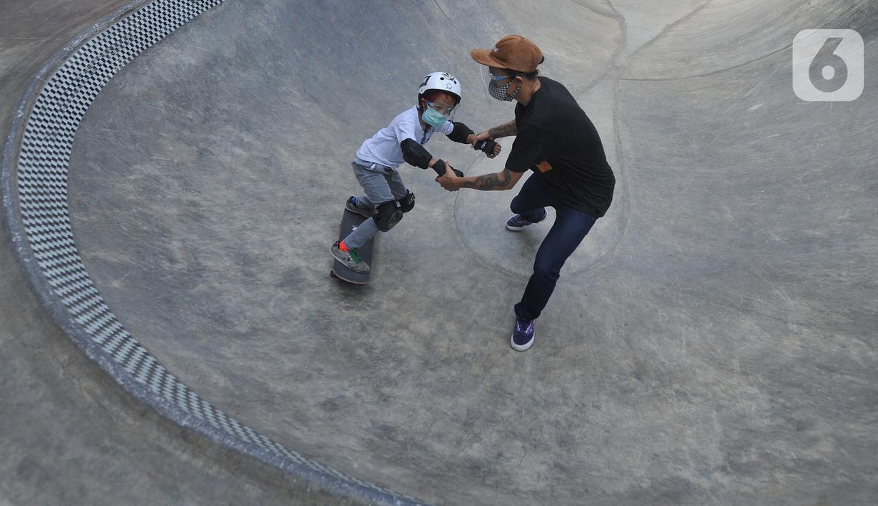 Instruktur melatih seorang anak menggunakan skateboard dengan memakai masker dan face shield di Crooz Shophouse di kawasan Duren Tiga, Jakarta Selatan, Minggu (2/8/2020). Mereka kembali melakukan latihan seminggu dua kali dengan menerapkan protokol kesehatan. (merdeka.com/Arie Basuki)