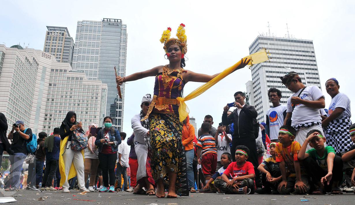Seniman membawakan Tari Pendet khas Bali dalam parade kebudayaan bertajuk 'Kita Indonesia' di kawasan Bundaran HI, Jakarta, Minggu (4/12). Para peserta Parade Kebudayaan tampak antusias menyaksikan tarian itu. (Liputan6.com/Angga Yuniar)