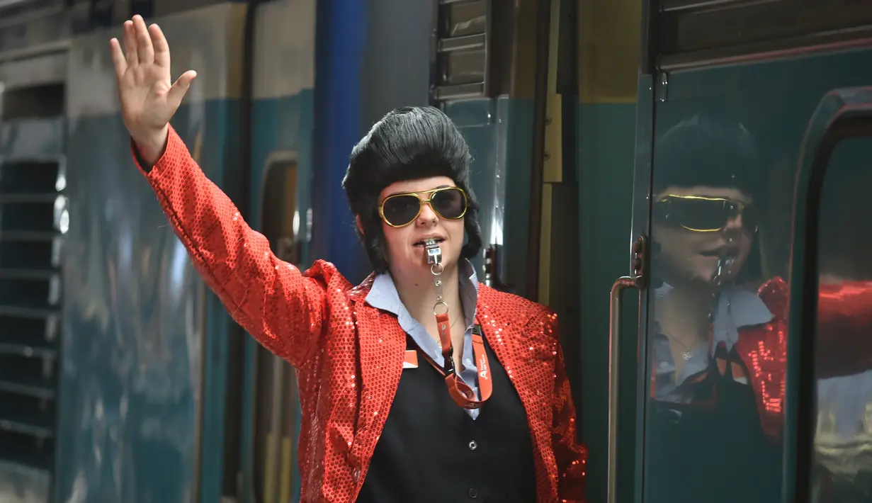 Kondektur kereta berpakaian seperti Elvis memberi isyarat agar kereta meninggalkan stasiun Central untuk membawa orang ke Parkes Elvis Festival, di Sydney (11/1). (AFP Photo/Peter Parks)