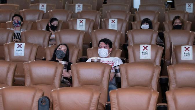 Pengunjung memakai masker duduk menjauh untuk mencegah penyebaran Covid-19 ketika mereka menonton film di bioskop Paragon Cineplex di Bangkok, Thailand, Senin (1/6/2020). (AP Photo/Sakchai Lalit)