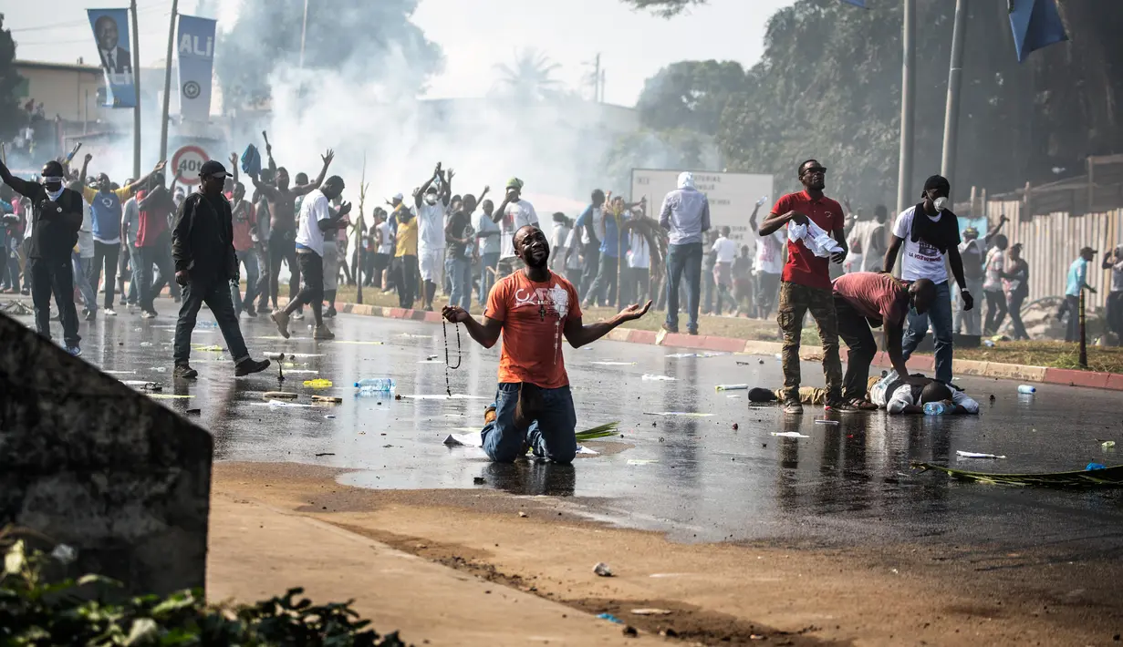 Seorang pendukung kandidat oposisi Gabon, Jean Ping berdoa di depan pasukan keamanan yang menghalangi aksi mereka di Ibu Kota Gabon, Libreville, Rabu (31/8). Demonstrasi meletus setelah Presiden Gabon, Ali Bongo terpilih kembali. (MARCO LONGARI/AFP)