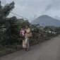 Gunung Semeru menjulang di atas desa Lumajang, Jawa Timur, setelah meletus sehari sebelumnya, Minggu (17/1/2021). Gunung Semeru kembali erupsi dan mengeluarkan awan panas guguran sejauh 4,5 kilometer pada Sabtu (16/1). (Juni Kriswanto / AFP)