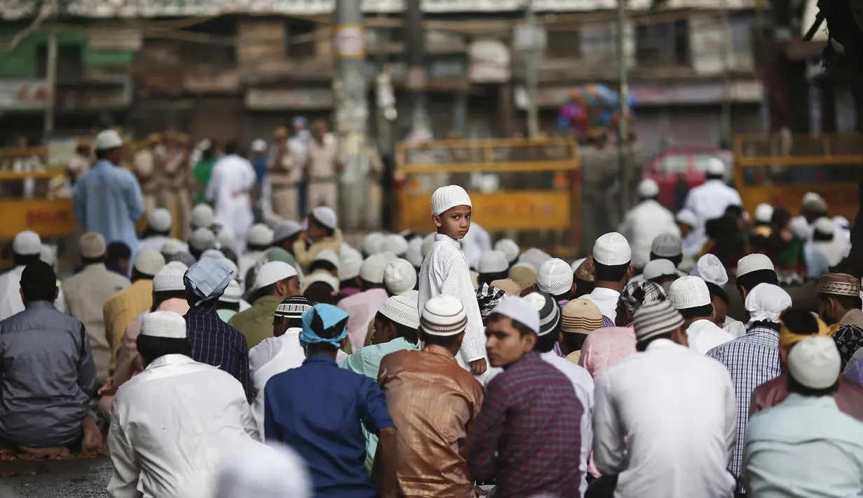 Seorang anak lelaki berdiri diantara para jemaah yang melaksanakan salat Idul Fitri di Masjid Jama, India, Selasa (29/7/14). (REUTERS/Adnan Abidi)