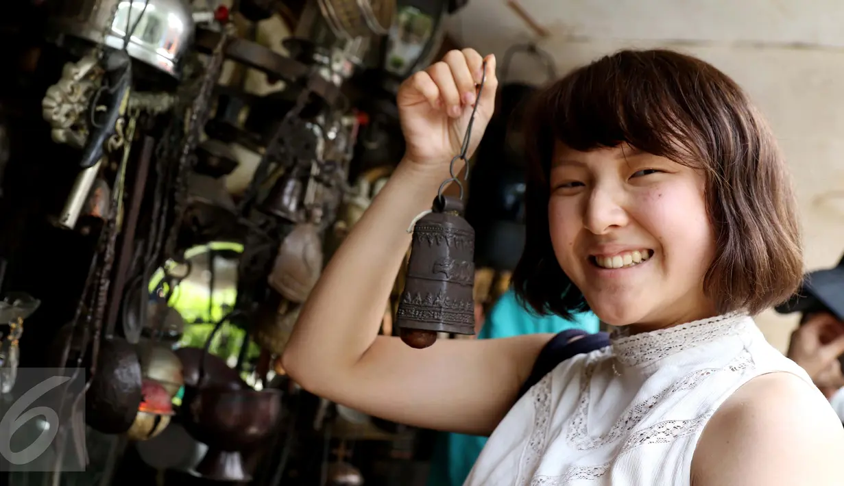 Turis asing menunjukan lonceng tua di kawasan penjual barang antik di Jalan Surabaya, Jakarta, Minggu (10/9). Kisaran harga di kawasan ini mulai dari puluhan ribu rupiah hingga puluhan juta rupiah. (Liputan6.com/Gempur M. Surya)