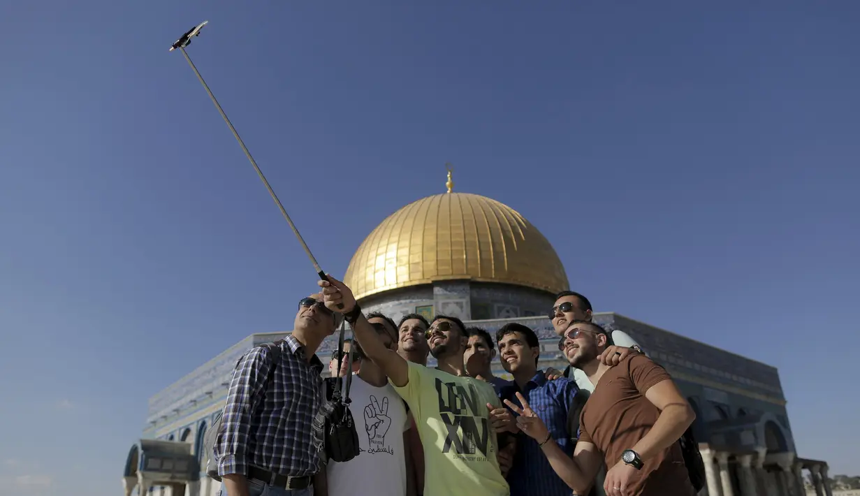 Hakem Shtayeh (tengah) berfoto selfie dengan teman-temannya di depan kubah Ash-Shakhrah di area Masjid Al-Aqsa, Yerusalem, 29 Juni 2015. (REUTERS/Ammar Awad)