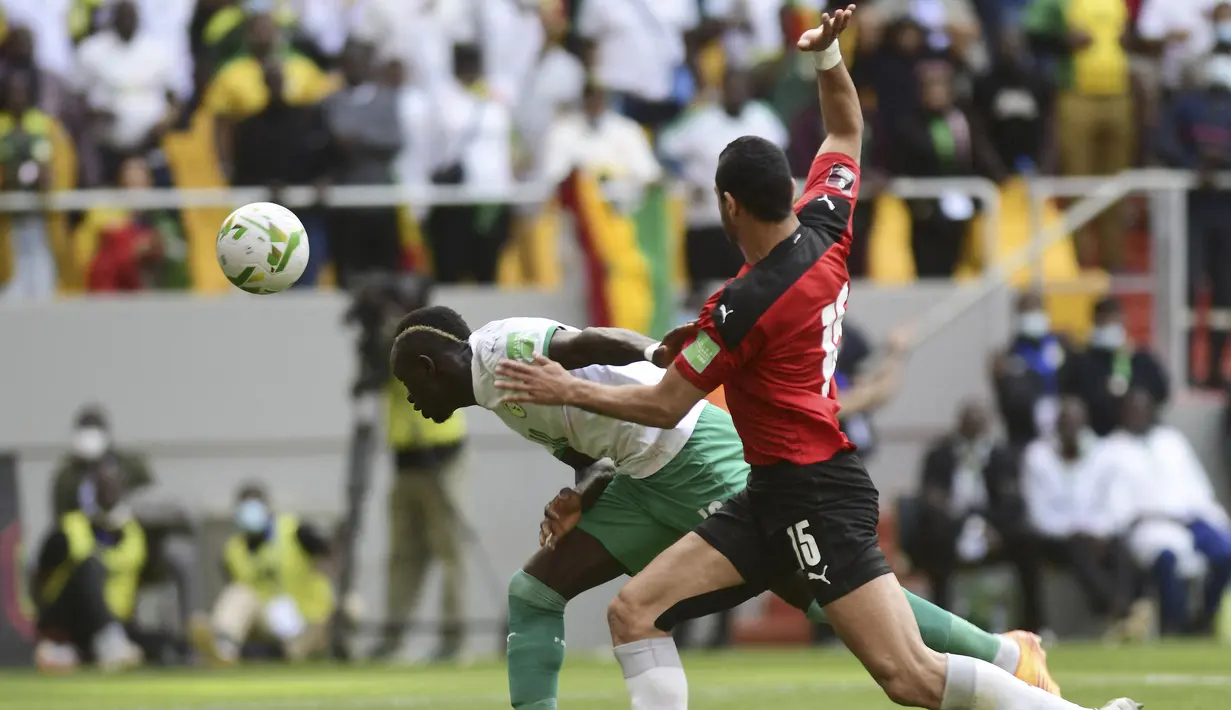 Penyerang Senegal Sadio Mané berebut bola dengan bek Mesir Rami Rabia pada Kualifikasi Piala Dunia 2022 zona Afrika di Stade Me Abdoulaye Wade, Rabu (30/3/2022) dini hari WIB. Senegal dipastikan lolos ke Piala Dunia 2022 setelah menang adu penalti atas Mesir 3-1. (SEYLLOU / AFP)