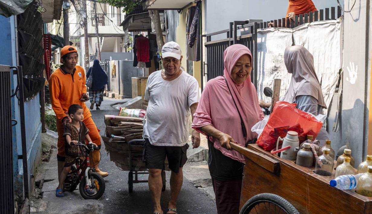 Seorang pria mengantarkan sampah rumah tangga anorganik, berupa kardus dan botol plastik, untuk disetorkan ke bank sampah setempat, Jakarta, Kamis 4 Juni 2026, sebagai bagian dari instruksi Pemprov DKI yang mewajibkan warga memilih dan memilah sampah untuk mengurangi beban sampah yang semakin menumpuk di ibu kota. (BAY ISMOYO/AFP)