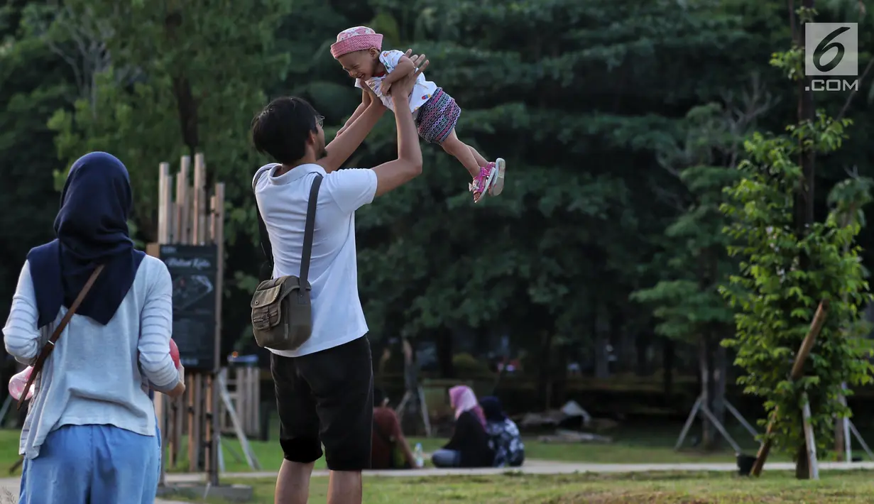 Warga bermain bersama seorang anak di Hutan Kota kawasan Gelora Bung Karno, Jakarta, Minggu (6/1). Hutan Kota yang dimiliki Jakarta tersebut bebas polusi dan sejuk. (Liputan6.com/JohanTallo)