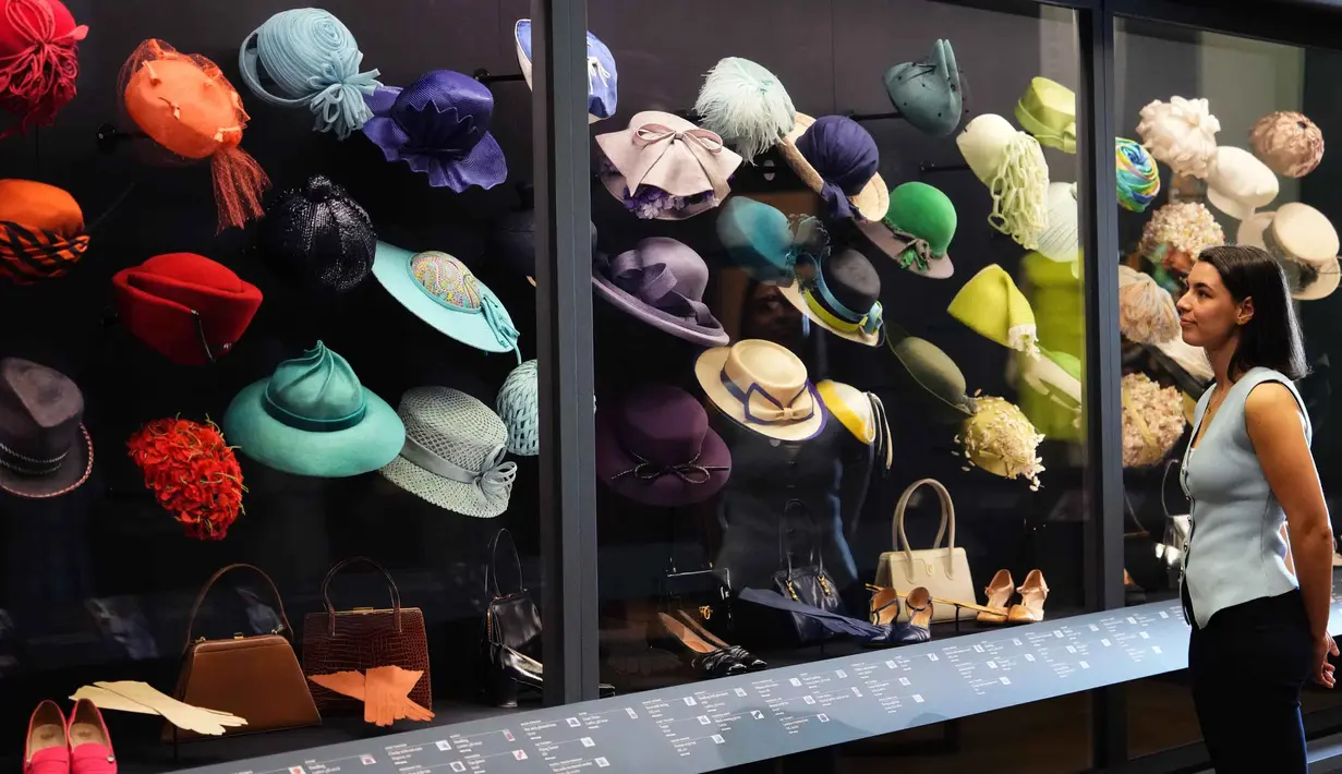 Acara yang akan menampilkan ratusan busana dan aksesori ikonik, menjadikannya sebagai pameran mode terbesar sang Ratu. Tampak dalam foto, seorang anggota staf Royal Collection Trust melihat ke arah topi, tas, dan sepatu yang dikenakan oleh Putri Elizabeth, yang dipamerkan di pameran 'Queen Elizabeth II: Her Life in Style', di The King's Gallery, Istana Buckingham, London, Inggris, Kamis 9 April 2026. (AP Photo/Kirsty Wigglesworth)