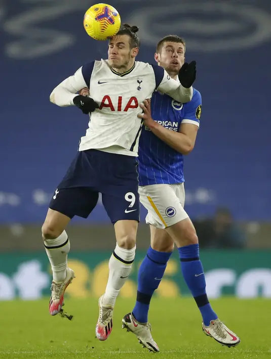 Penyerang Tottenham Hotspur, Gareth Bale melompat saat berebut bola dengan bek Brighton & Hove Albion, Adam Webster dalam pekan ke-21 Liga Inggris di Amex Stadium pada Senin (1/2/2021) dini hari WIB. Brighton taklukkan Tottenham Hotspur dengan skor 1-0. (Andrew Boyers/Pool via AP)