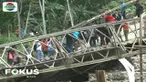 Truk sarat muatan material bangunan ini pun terguling setelah tiang penyanggah jembatan roboh akibat tidak kuat menahan beban di atasnya.