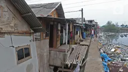 Warga berjalan melintasi sejumlah rumah di kawasan Kampung Tembok, Muara Angke, Jakarta Utara, Rabu (4/3/2020). Warga Kampung Tembok terpaksa harus menembok dan menutup akses jalan warga karena saat musim hujan kerap terjadi rob. (Liputan6.com/Herman Zakharia)