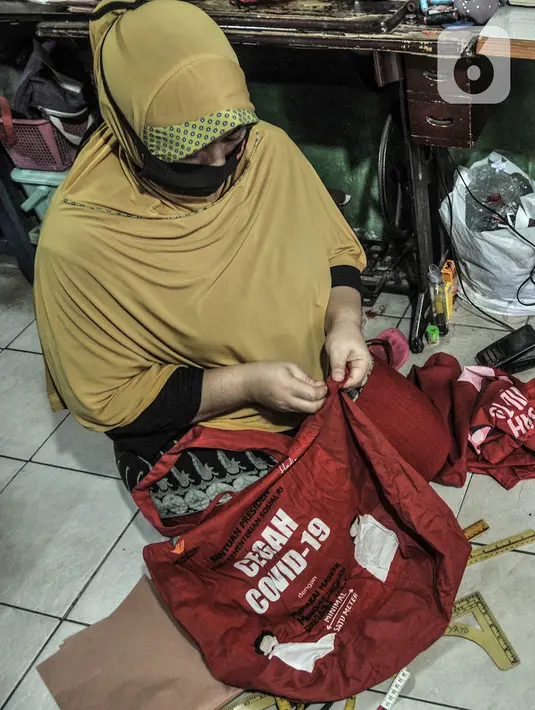 Siti Zahro (44) menyelesaikan pembuatan celemek berbahan tas bansos Covid-19 di industri jahit rumahan KG-Lupe Fashion, Salemba, Jakarta, Senin (16/11/2020). Dalam sehari Siti mampu memproduksi tiga buah celemek. (merdeka.com/Iqbal S. Nugroho)