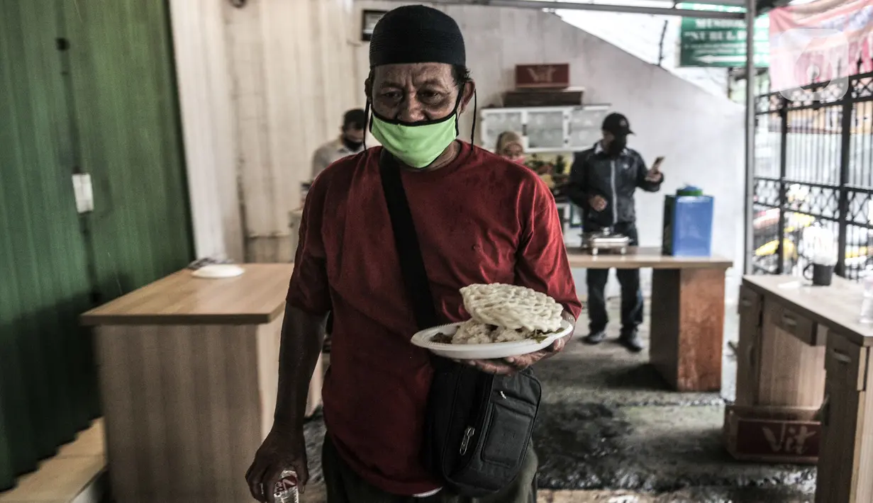 Warga membawa satu porsi makanan gratis di Jalan Basuki Rachmat, Cipinang Muara, Jakarta, Senin (8/3/2021). Layanan ini berlangsung setiap Senin hingga Jumat mulai pukul 12.00 sampai 14.00 WIB dengan menyediakan 70 hingga 100 porsi makanan per hari. (merdeka.com/Iqbal S Nugroho)