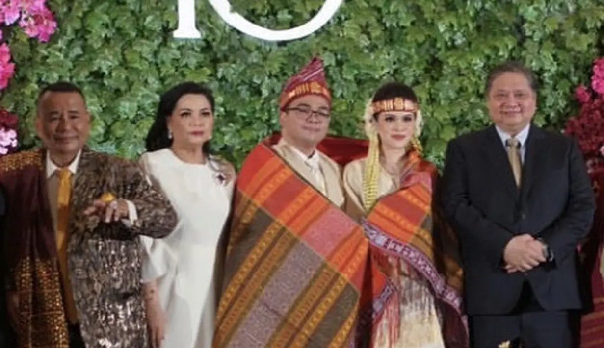 Airlangga Hartarto Menteri Koordinator Bidang Perekonomian RI hadir dengan setelan jas hitam dengan inner kemeja putih lengkap berdasi keemasan. Sedangkan sang istri tampil elegan mengenakan dress putih. [@airlanggahartarto_official]
